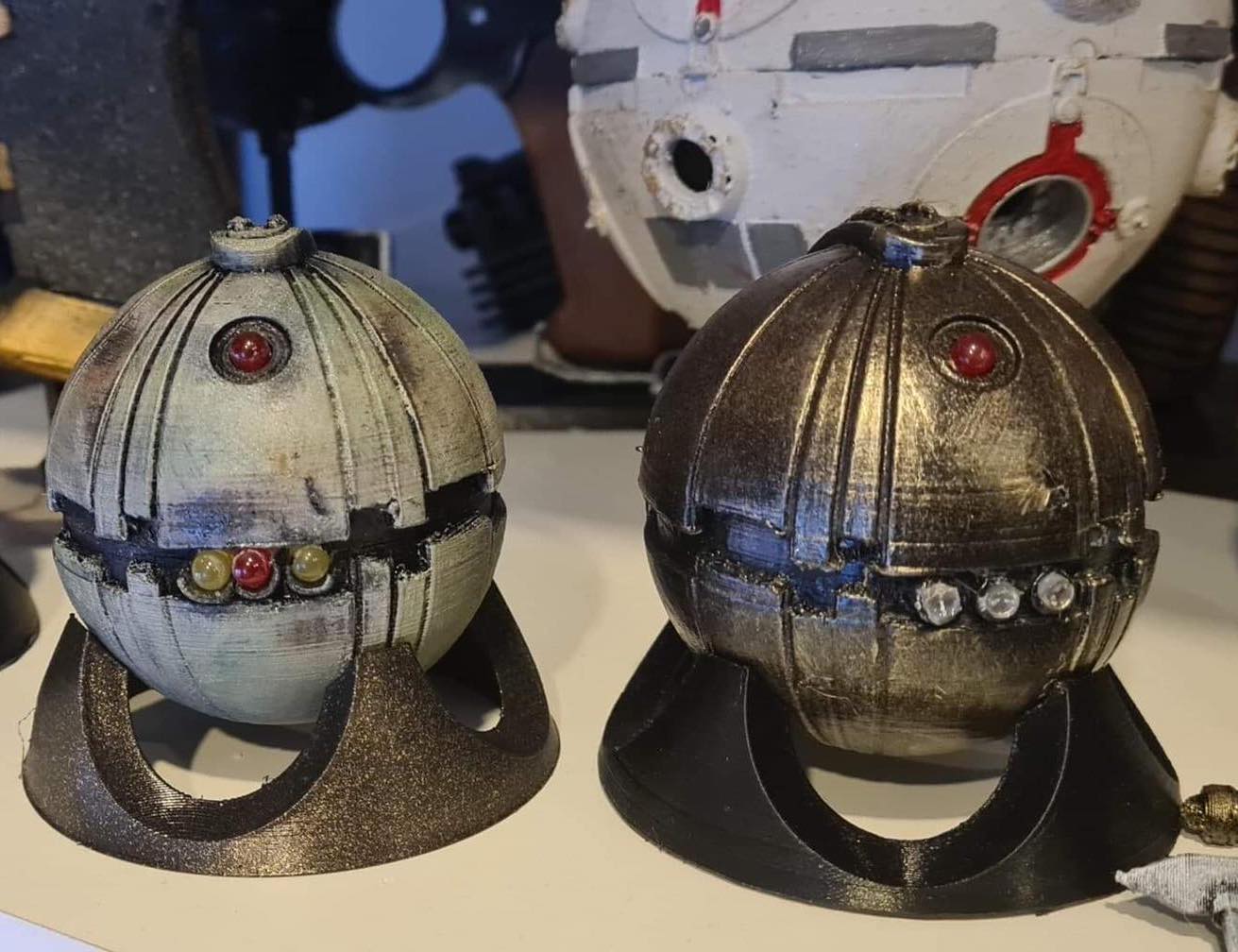 A photo of a 3D printed thermal detonator device, set on a display stand.